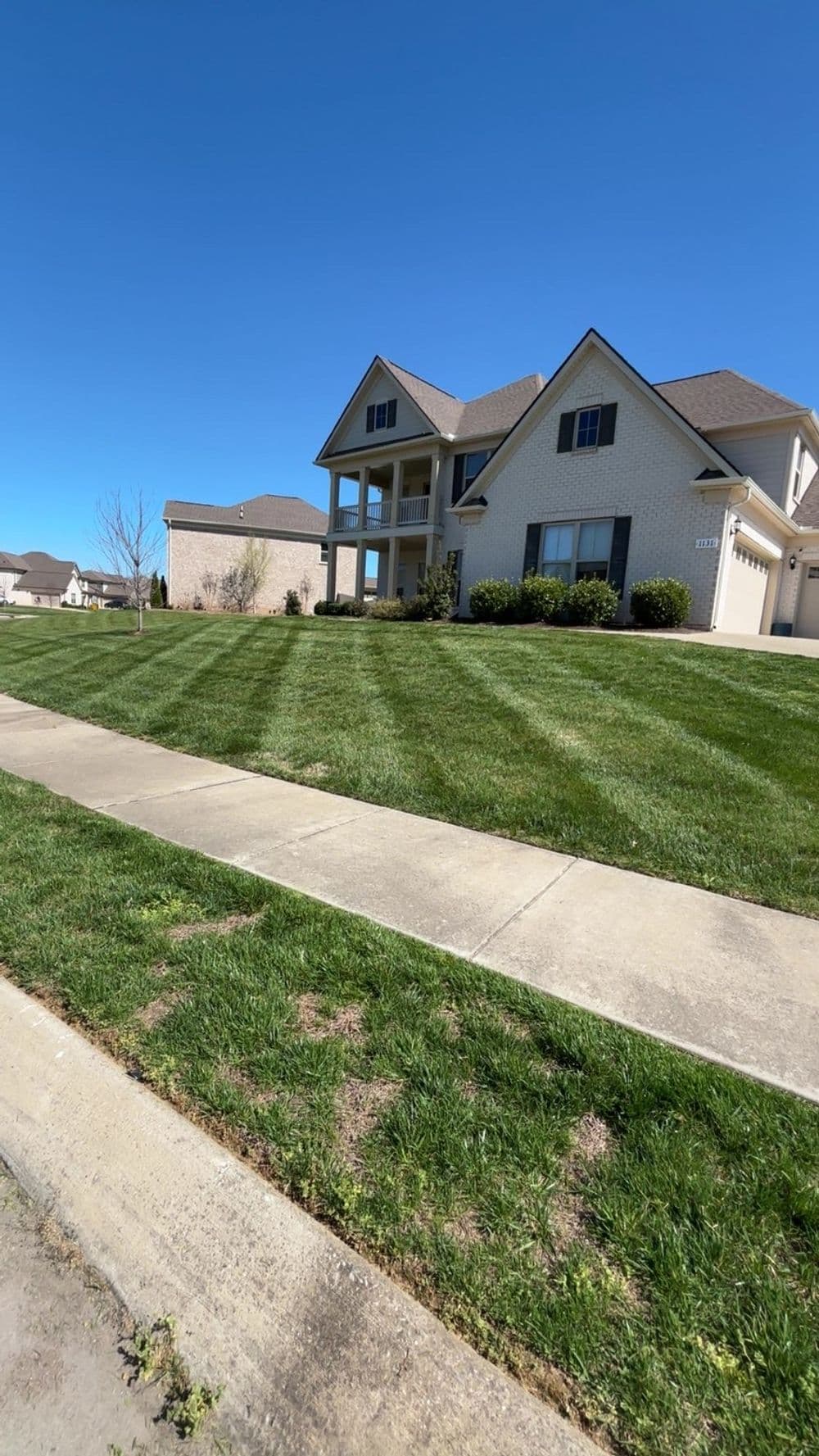 Modern two-story house with manicured lawn and clear blue sky. Ideal suburban living.